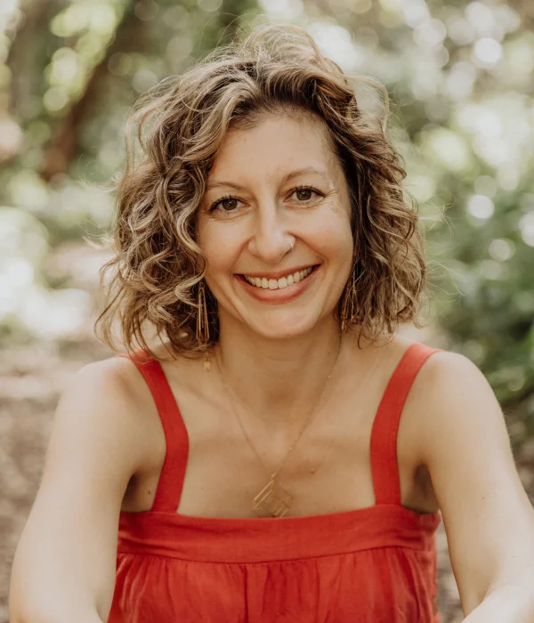 Alison Yanni, a blond woman with short curly hair, with a red shirt, smiling at the camera.