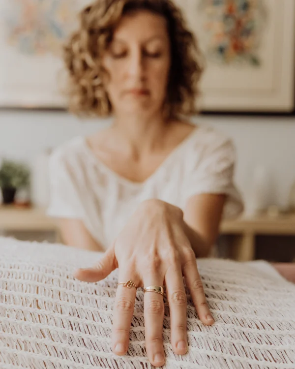 Alison wears a white shirt, has her eyes close while resting her hand in a relaxed woman's belly