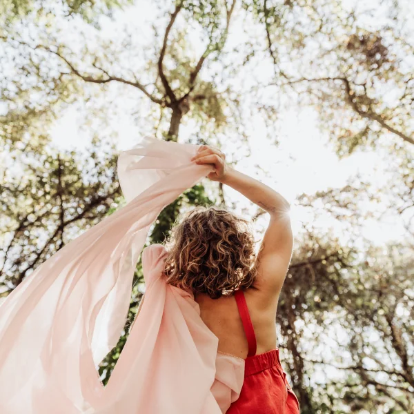 Alison looking up to the sky, waving a light pink fabric around