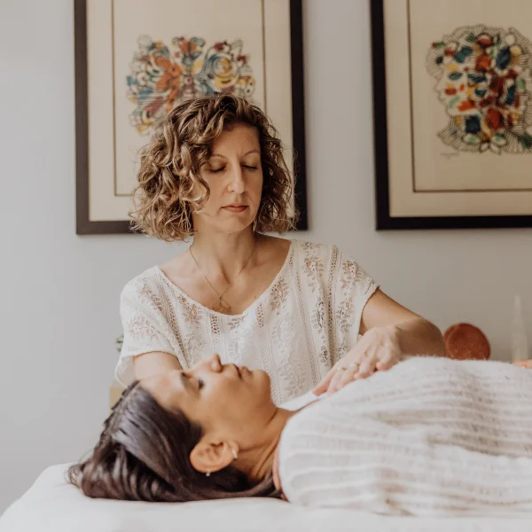 Alison wears a white shirt, has her eyes close while resting her hand in a relaxed woman's chest
